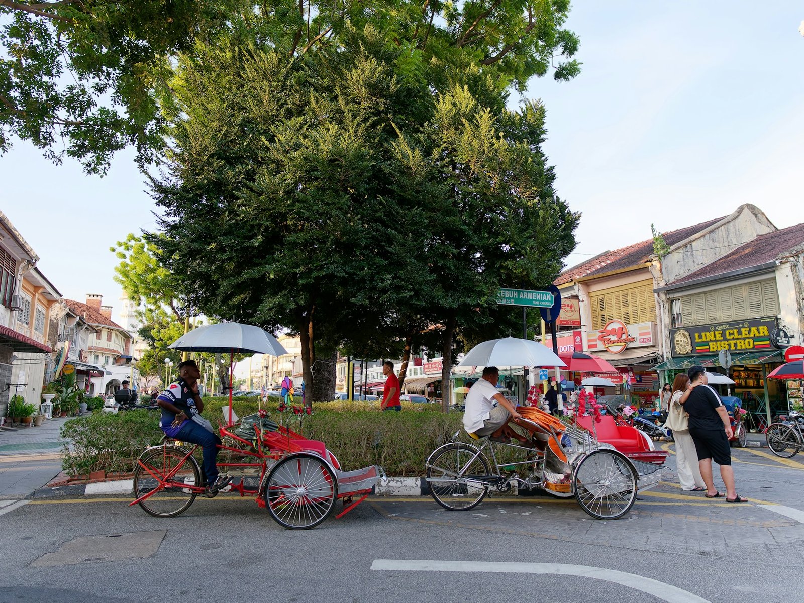 Heritage rickshaws and travelers on a George Town street in Penang